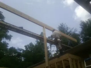 Carpenter setting a ridge beam over a new addition frame — Ice Dam Removal by Roofing Brothers in Ames