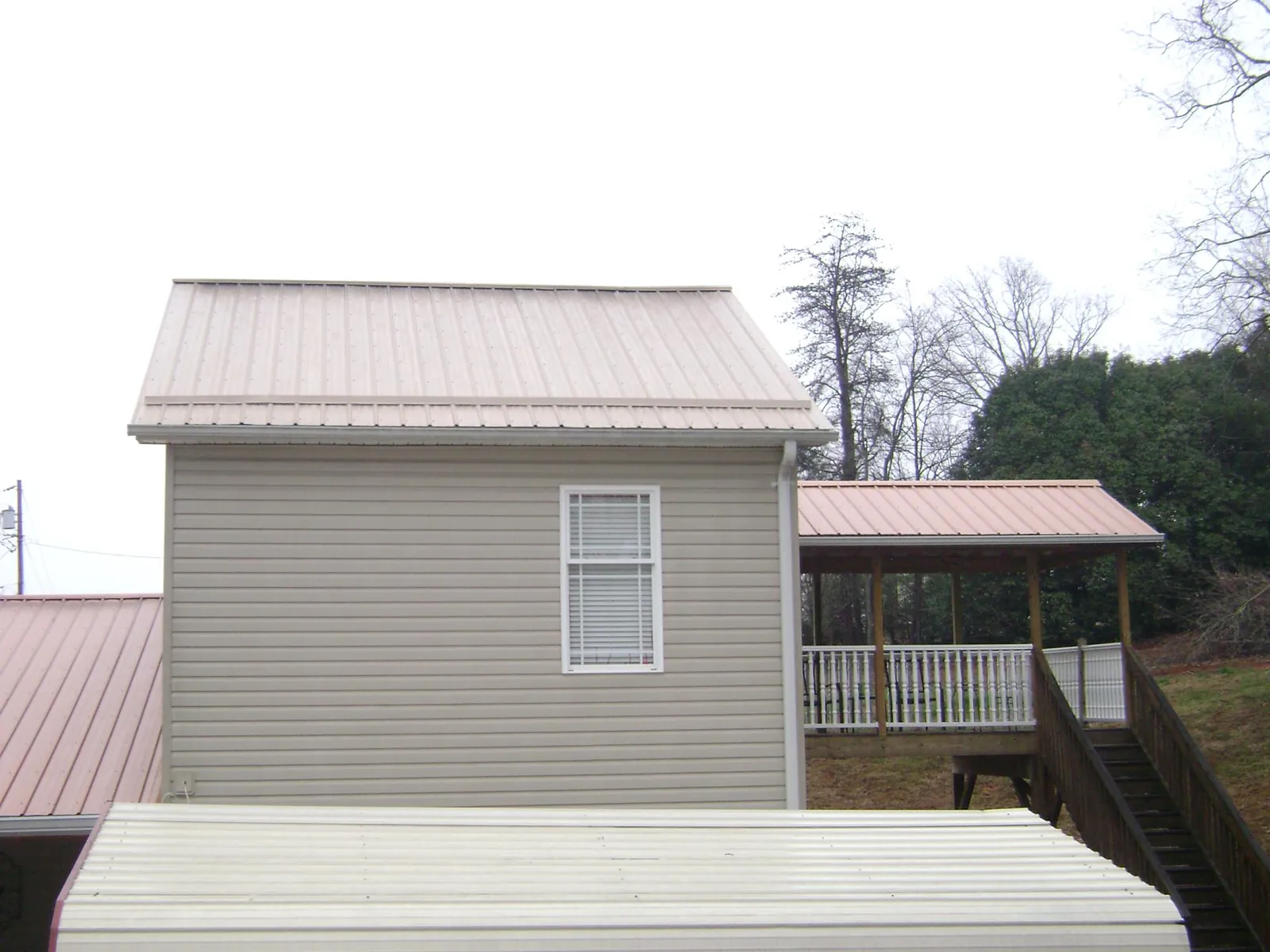 Tan metal roofs on a two story addition and attached porch, from a Roof Replacement job in Ames
